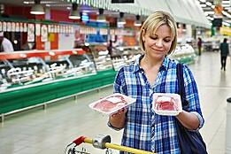 Consumer comparing meat packaging in a retailer. 